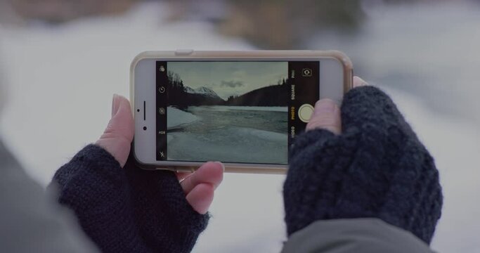 Person holds up their phone to take a picture of a partially frozen lake in the Kenai National Wildlife Refuge, Alaska