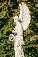 Statue of ancient beautiful winged angel in downtown park of Potsdam in beginning of Autumn at...