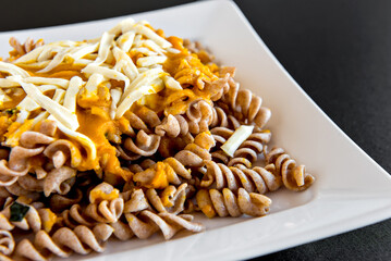 Fusilli pasta with pumpkin sauce and colonial cheese, homemade food dish close up.