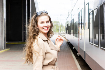 Portrait of beautiful woman (European, American female) in her 30s, staying on platform of railway...