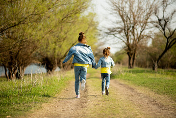Two cute sister girls are running down an empty country road. Spring. Freedom. Childhood. Family.