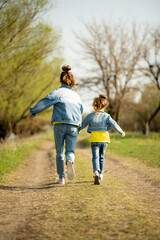 Two cute sister girls are running down an empty country road. Spring. Freedom. Childhood. Family.