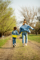 Fototapeta premium Two cute sister girls are running down an empty country road. Spring. Freedom. Childhood. Family.