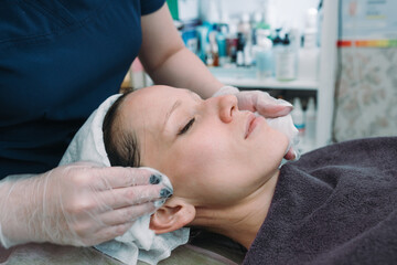 Cosmetologist apply facial treatment on woman face in beauty saloon. Skincare. Cosmetic procedure.