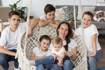 Beautiful young mother and her five kids at home in the living room