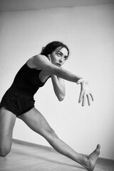 Black and white photo of young emotional woman performing original dance at home