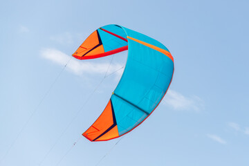 Close-up detail one bright blue orange kitesurf wings kite equipment fly against clear sky t on bright sunny day against at kiter riding surf school camp. Active travel sport concept