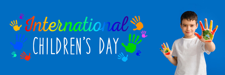Cute little boy with hands in paint on blue background. International Children's Day