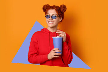 Beautiful redhead woman with soda on orange background