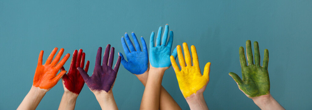 Many children's hands in paints on blue background