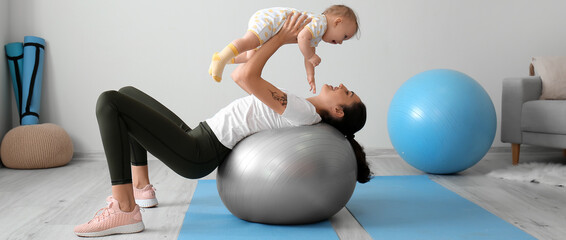 Sporty young woman and her baby doing exercises with fitball at home