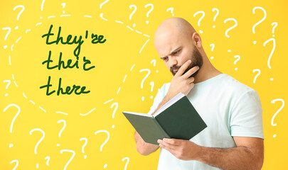 Thoughtful man studying English grammar on yellow background - obrazy, fototapety, plakaty