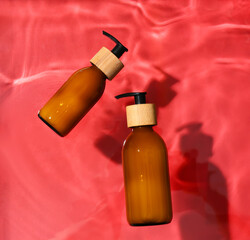 Bottles of cosmetic product in water on red background