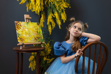 A girl sits near a mimosa and paints a picture in a blue dress mimosa brush little girl, for...