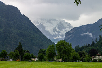 Beautiful view of the green lawn against the mountains and cloudy sky. Jungfrau, Switzerland.