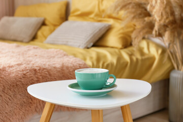 Cup of coffee on bedside table in room, closeup