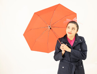 cute white asian woman standing, wearing a blue trench coat, pink blouse, looking at the sky under a cute red umbrella, on white background