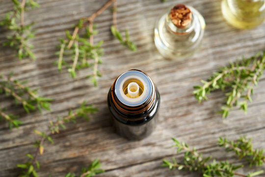A dark bottle of thyme essential oil with fresh thyme