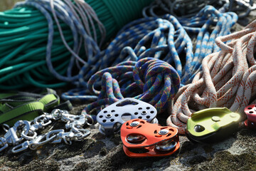 Different belay devices and ropes on rock, closeup. Climbing equipment - obrazy, fototapety, plakaty