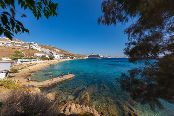 Fototapeta premium Mykonos, Greece - August 1, 2021: Panoramic wide angle view over the beach side of the island Mykonos. Mykonos is located in the cyclades archipelago in the Aegean Sea. Turquois water on sand beach.