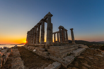 Fototapeta na wymiar Amazing colorful sunset at the Temple of Poseidon, archaeological site of Sounion, Attica. Cape Sounion, Lavrio, Greece. A sunset behind the citadel on a hill at the shoreline of Mediterranean Sea.