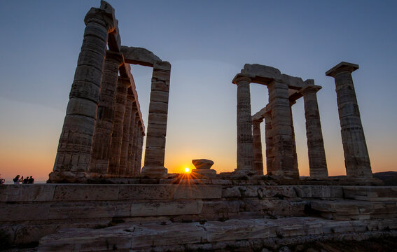 Amazing colorful sunset at the Temple of Poseidon, archaeological site of Sounion, Attica. Cape Sounion, Lavrio, Greece. A sunset behind the citadel on a hill at the shoreline of Mediterranean Sea.