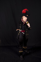 Vertical shot of a female holding a glass in a pirate costume on a black background