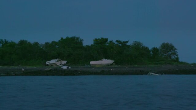 Boats Shipwrecked At Hart Island, Solemn Burial Site For Unidentified Dead, From The Water At Night.