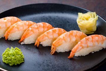 sushi with shrimp on a black plate on blue concrete table macro close up