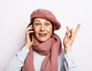 Elderly woman wearing pink scarf and hat with smartphone