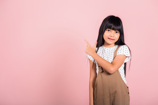 Asian Little Kid 10 Years Old Point With Index Finger Up At Studio Shot Isolated On Pink Background, Happy Child Girl Lifestyle Pointing To Empty Place