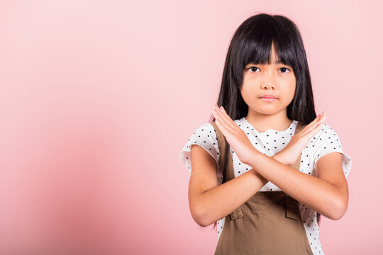 Stop Gesture. Asian Little Kid 10 Years Old Showing Two Hands Cross Arms Say No X Sign At Studio Shot Isolated On Pink Background, Happy Child Girl Disagreement Opposition