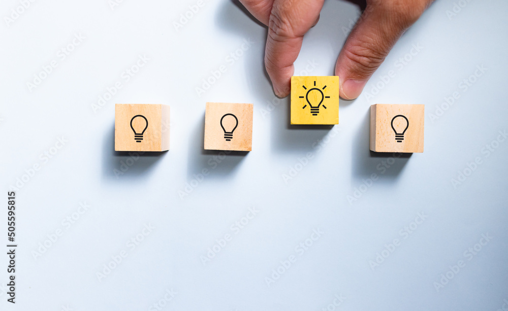 Poster top view hand pick wooden blocks with light bulb from the row. concept for creative and design solut