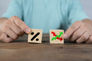 Businessman holds wooden blocks with percent and up or down arrow. Mortgage and loan rates. Interest rate, stocks