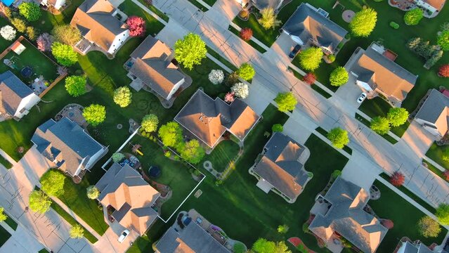 Springtime aerial view, looking straight down on nice neighborhoods with green lawns and blossoming trees.