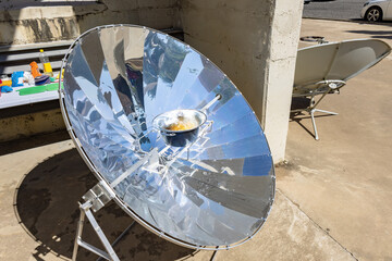 Cooking with sun energy, parabolic solar oven in the middle of cooking a dish thanks to solar energy - obrazy, fototapety, plakaty