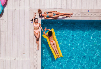 Friends in swimsuit who tan in the sunbed in a swimming pool