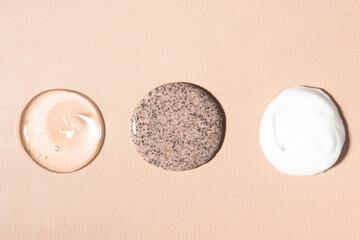 Drops of transparent gel, body cream and scrub on a beige background. Texture of cosmetic products...