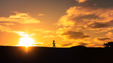 Happy child running free in a meadow sunset