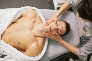 Fototapeta na wymiar a man is given a therapeutic massage of the body and face in a spa salon