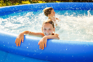Summer season concept background. Happy friends in an inflatable pool in the garden, refreshing...