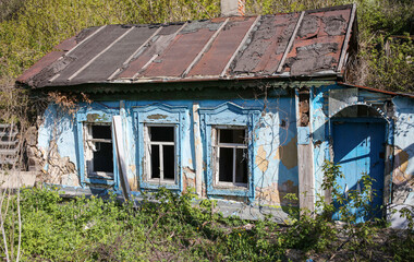 Old crumbling house overgrown with plants.