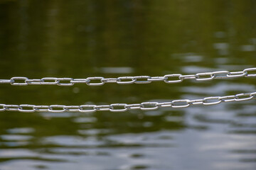 Two metal chains above the water surface close-up