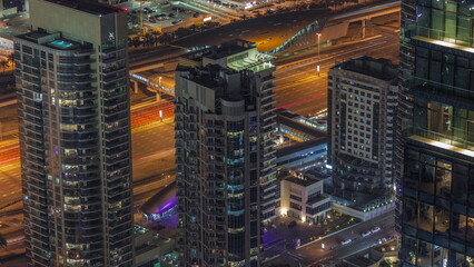 Dubai marina towers with traffic on Sheikh Zayed road near metro station night timelapse.