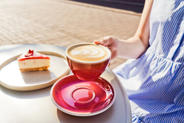 Cup of latte coffee in womans hands.