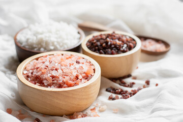 different kinds of salt in wooden cup placed on white cloth, food and health concept.