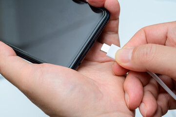 Man's hand connecting type-c cable to smartphone.