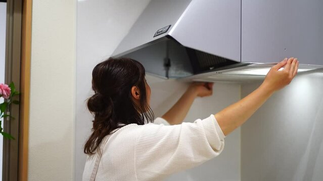 換気扇のフィルターを取り付ける女性