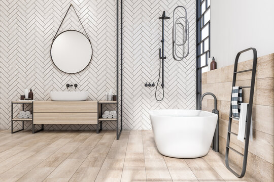 Light eco style bathroom with wooden floor, sink base cabinet and wall decoration, round mirror on herringbone ceramic tale wall and white bathtub. 3D rendering