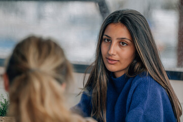 young brunette latin american woman talking to blonde caucasian friend
